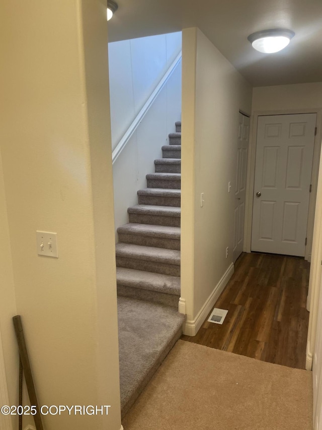 hallway featuring visible vents, dark wood finished floors, stairway, and baseboards