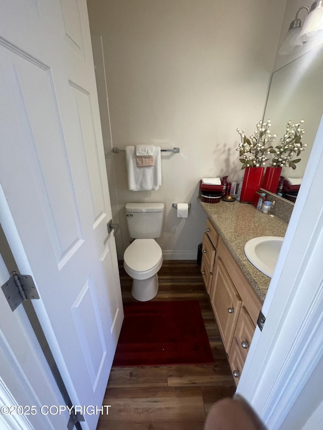 bathroom with baseboards, vanity, toilet, and wood finished floors