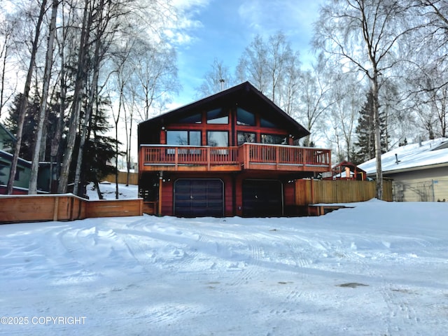 snow covered rear of property featuring an attached garage and a deck