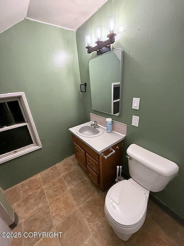 bathroom with lofted ceiling, vanity, and toilet