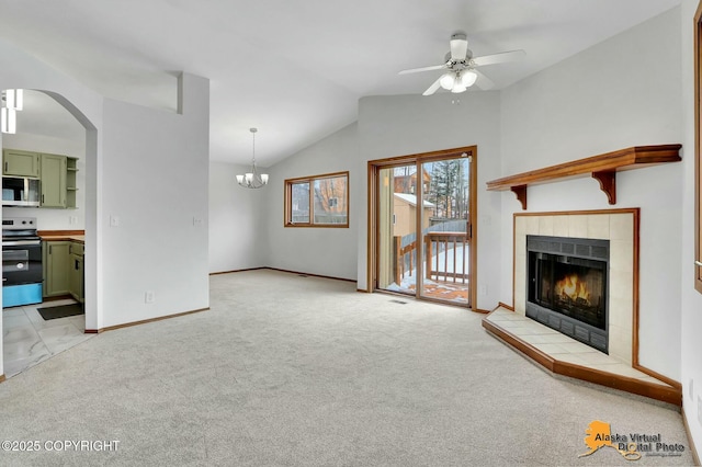 living room with lofted ceiling, a tile fireplace, ceiling fan with notable chandelier, and light colored carpet