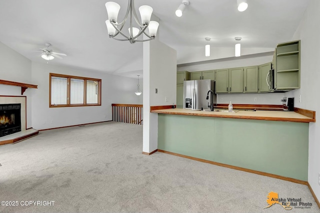 kitchen with lofted ceiling, hanging light fixtures, a peninsula, stainless steel appliances, and green cabinetry