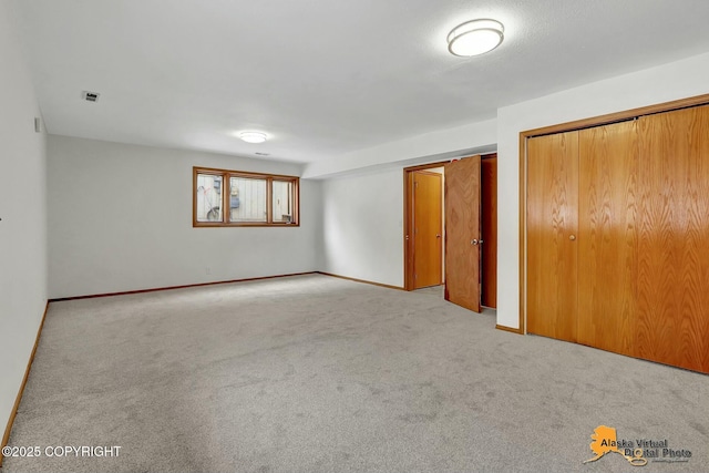 unfurnished bedroom featuring light carpet, baseboards, visible vents, and multiple closets