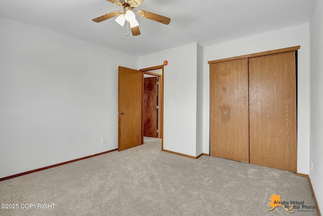 unfurnished bedroom with light carpet, ceiling fan, a closet, and baseboards