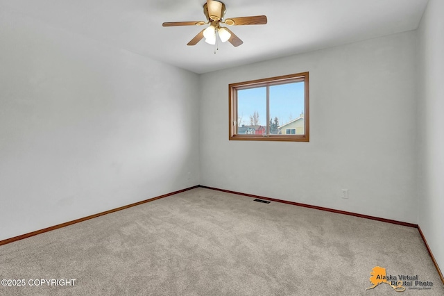 spare room featuring carpet floors, a ceiling fan, visible vents, and baseboards