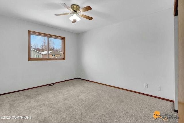 carpeted empty room with ceiling fan, visible vents, and baseboards