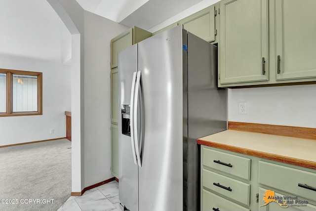 kitchen featuring green cabinetry, arched walkways, light countertops, and stainless steel refrigerator with ice dispenser