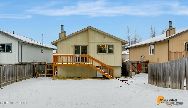 snow covered rear of property featuring a fenced backyard and a wooden deck