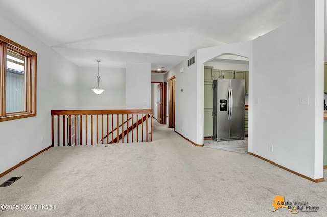 unfurnished room with light colored carpet, visible vents, and vaulted ceiling