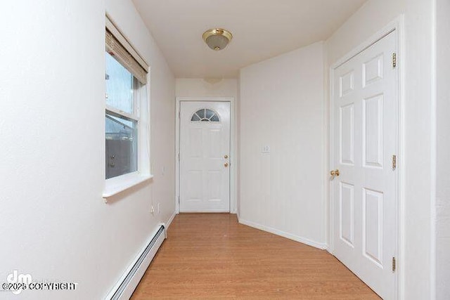 doorway to outside featuring a baseboard heating unit, light wood finished floors, and baseboards