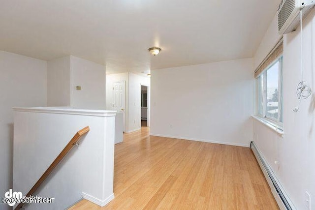 unfurnished room with light wood-style floors, a baseboard radiator, and baseboards