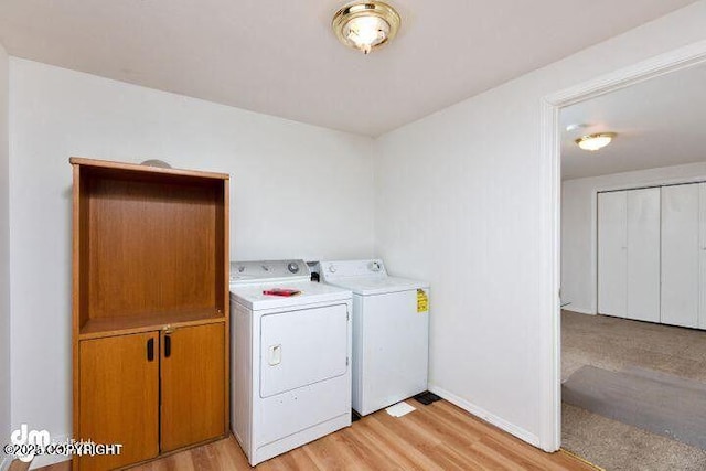 laundry area featuring light wood finished floors, baseboards, separate washer and dryer, and cabinet space