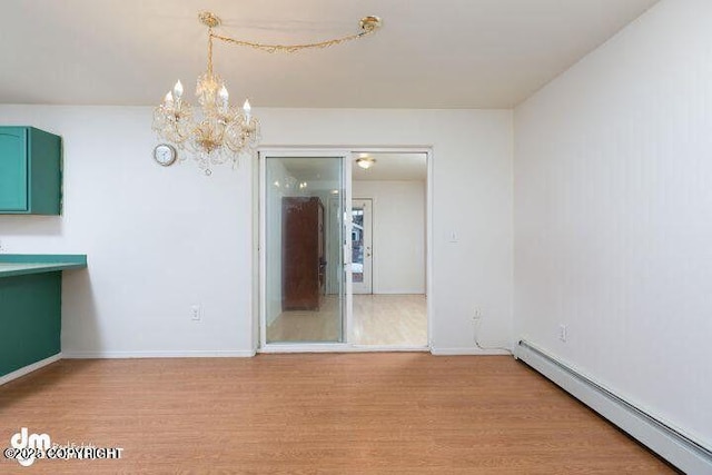 unfurnished room featuring light wood-style floors, a baseboard radiator, a notable chandelier, and baseboards