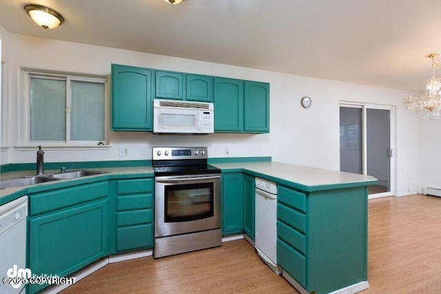 kitchen featuring a peninsula, white appliances, light wood-type flooring, and a sink