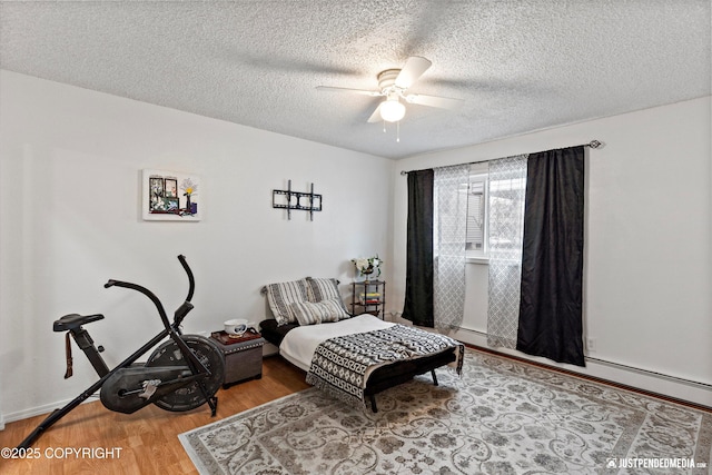 bedroom with a ceiling fan, a textured ceiling, and wood finished floors