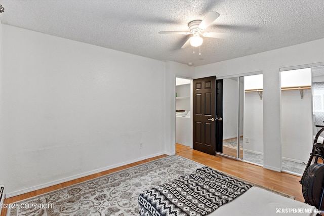 bedroom with baseboards, a textured ceiling, multiple closets, and wood finished floors