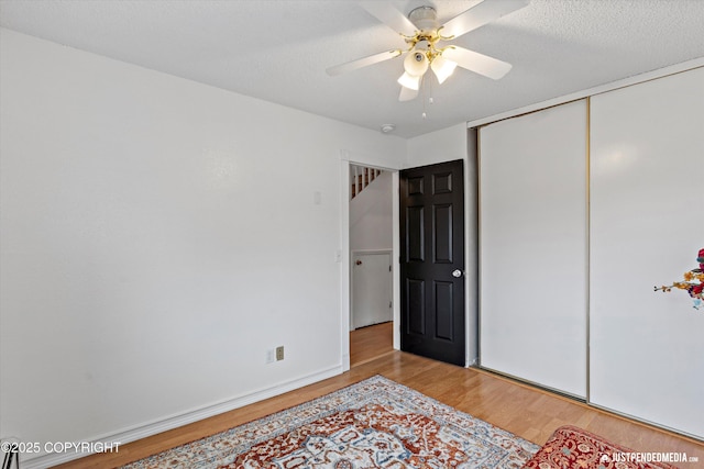 bedroom with a ceiling fan, baseboards, light wood-style flooring, and a closet