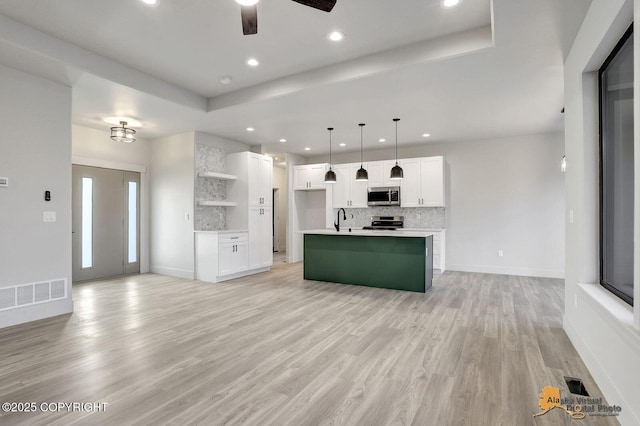 kitchen with visible vents, light wood-style flooring, appliances with stainless steel finishes, open floor plan, and backsplash