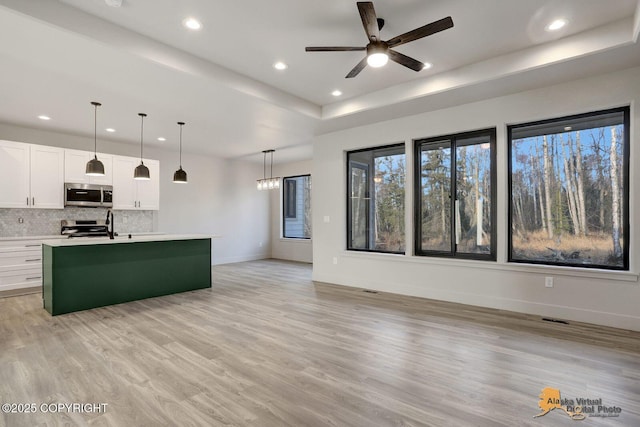 kitchen featuring tasteful backsplash, appliances with stainless steel finishes, a tray ceiling, light countertops, and white cabinetry