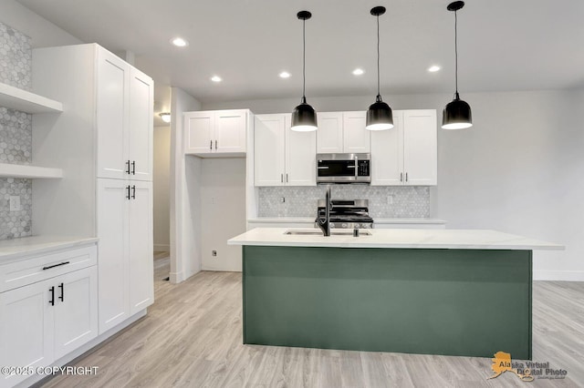 kitchen featuring light wood-style flooring, appliances with stainless steel finishes, light countertops, open shelves, and a sink