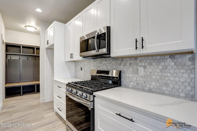 kitchen featuring tasteful backsplash, appliances with stainless steel finishes, white cabinets, and light wood-style flooring