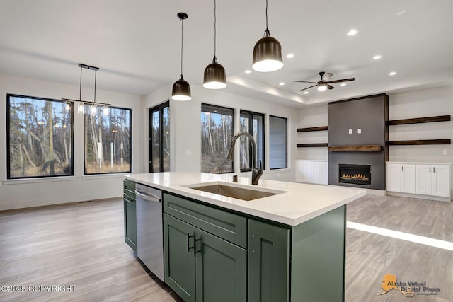 kitchen with a sink, light countertops, stainless steel dishwasher, light wood finished floors, and green cabinetry