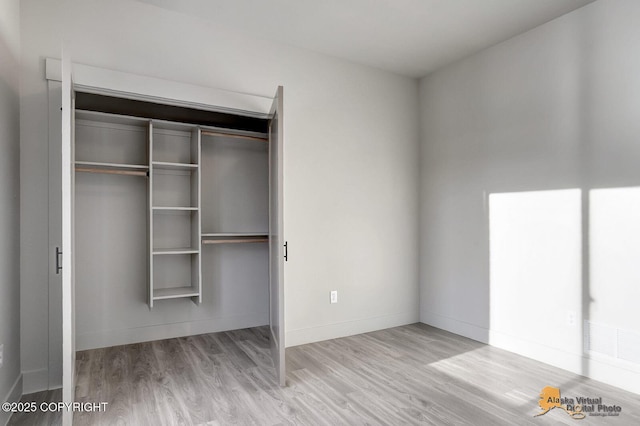 unfurnished bedroom featuring a closet, wood finished floors, and baseboards