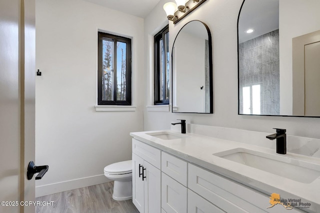 bathroom with wood finished floors, a sink, toilet, and baseboards