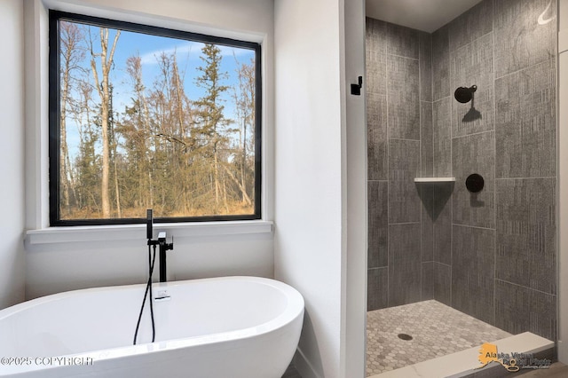 bathroom with a soaking tub and a tile shower