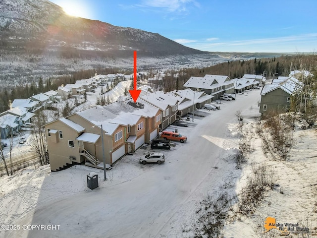 snowy aerial view with a residential view and a mountain view