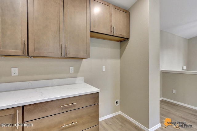 kitchen with light wood-style floors, baseboards, and light stone counters