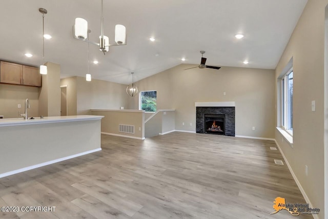 unfurnished living room featuring light wood-type flooring, visible vents, a sink, and lofted ceiling