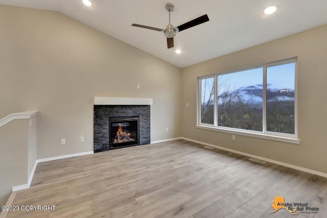 unfurnished living room with light wood-style floors, lofted ceiling, a fireplace, and baseboards