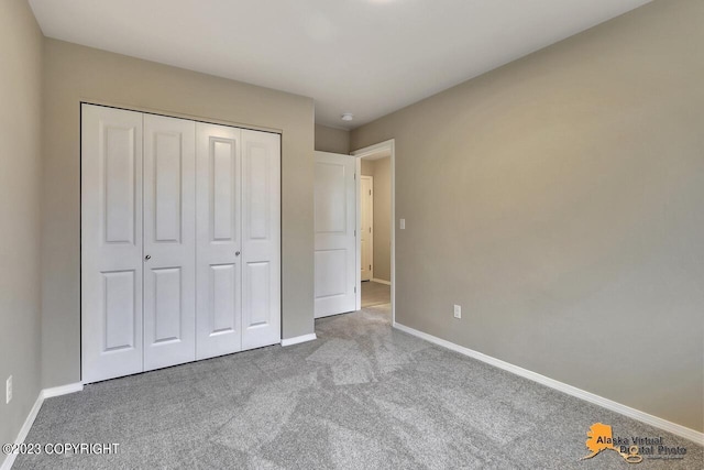 unfurnished bedroom with a closet, carpet flooring, and baseboards