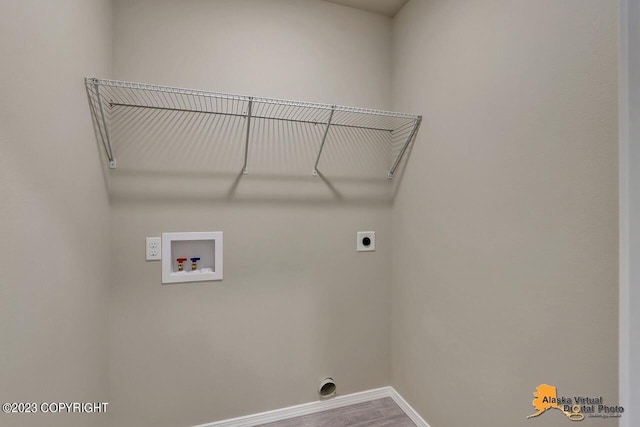 clothes washing area with washer hookup, electric dryer hookup, wood finished floors, laundry area, and baseboards