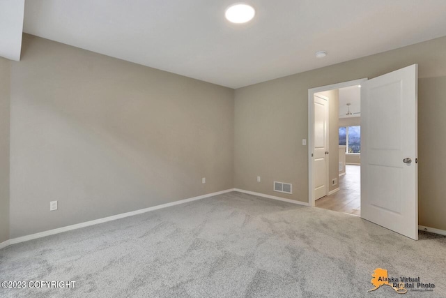 unfurnished room featuring light colored carpet, visible vents, and baseboards