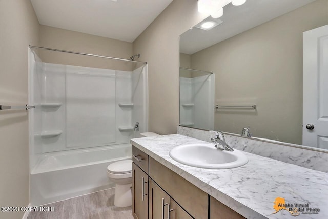 bathroom with toilet, vanity, wood finished floors, and shower / bathtub combination