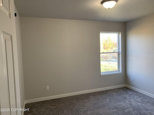 spare room with dark carpet and baseboards