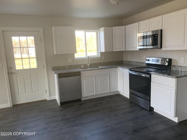 kitchen featuring dark wood finished floors, stainless steel appliances, stone countertops, white cabinets, and a sink