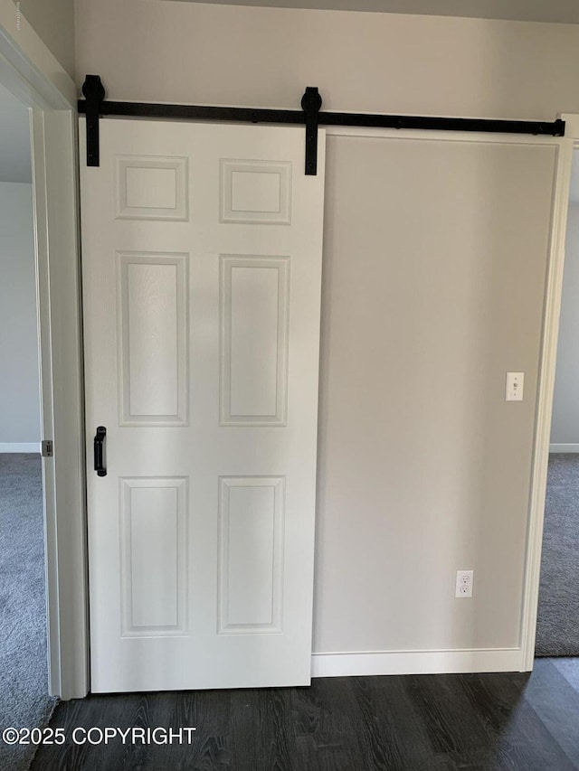 details with a barn door, baseboards, carpet flooring, and wood finished floors