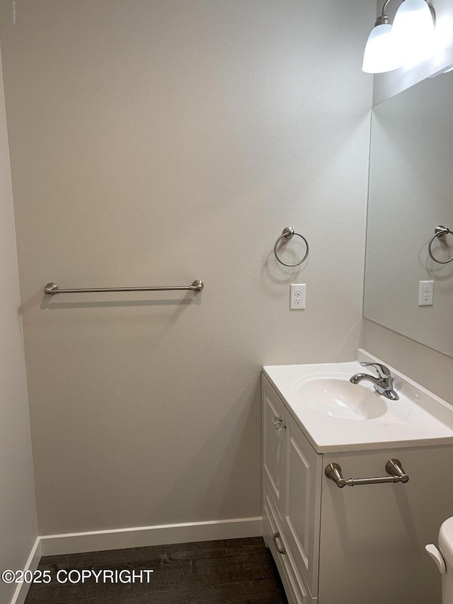 bathroom featuring toilet, vanity, and baseboards