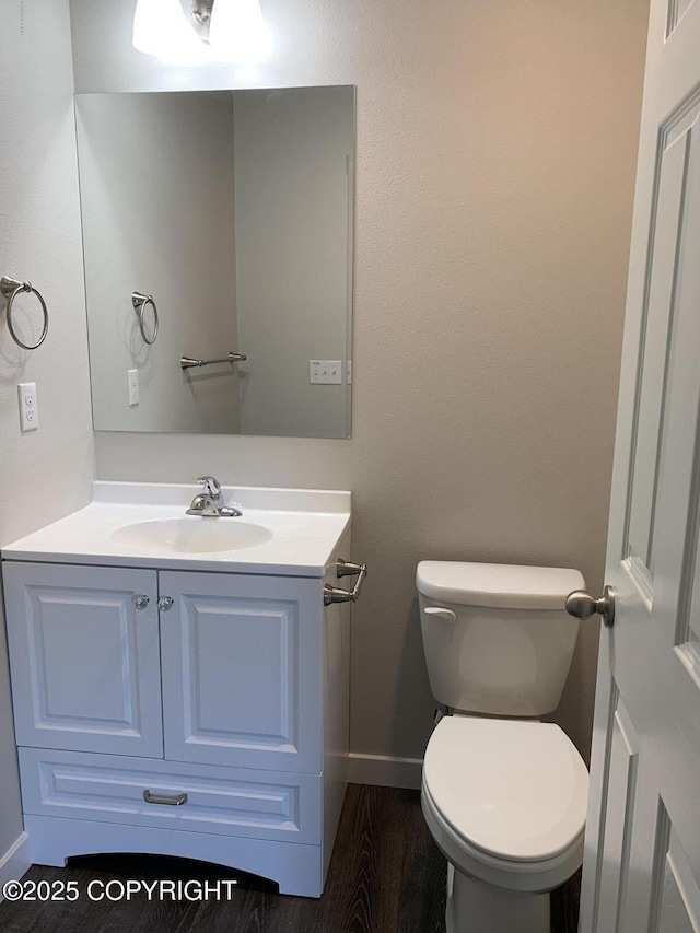 bathroom with toilet, baseboards, wood finished floors, and vanity