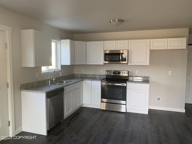 kitchen featuring baseboards, dark wood-style flooring, stainless steel appliances, white cabinetry, and a sink