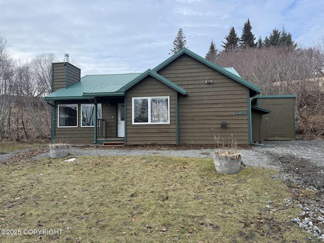 view of front of property with a front yard, metal roof, and a chimney