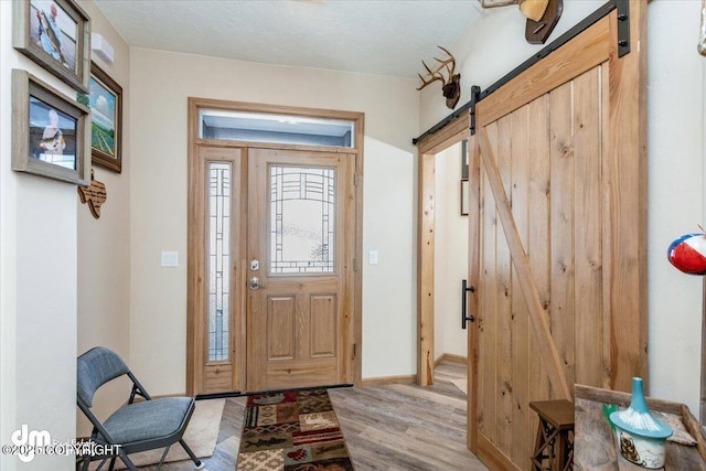 foyer with light wood-style floors, baseboards, and a barn door