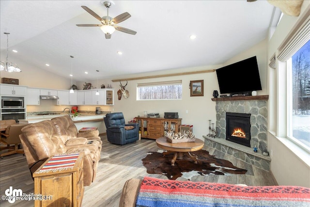 living area with a ceiling fan, vaulted ceiling, light wood-style floors, a fireplace, and recessed lighting