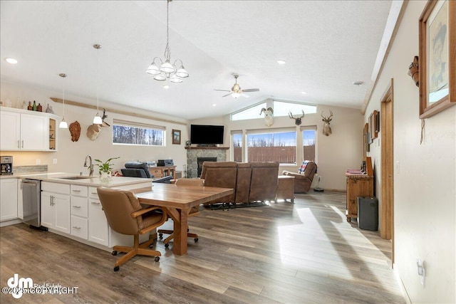 dining space featuring lofted ceiling, a healthy amount of sunlight, a fireplace, and light wood finished floors