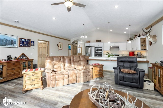 living room with arched walkways, lofted ceiling, ceiling fan, wood finished floors, and a textured ceiling