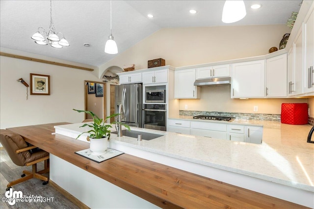 kitchen featuring white cabinets, appliances with stainless steel finishes, a peninsula, under cabinet range hood, and pendant lighting