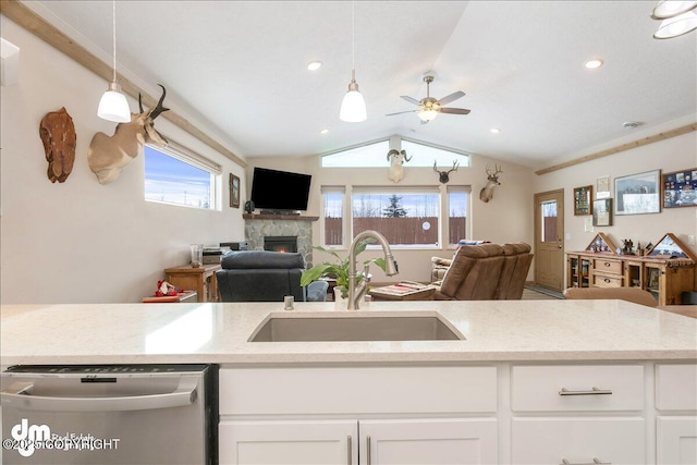 kitchen featuring hanging light fixtures, light stone countertops, open floor plan, and a sink